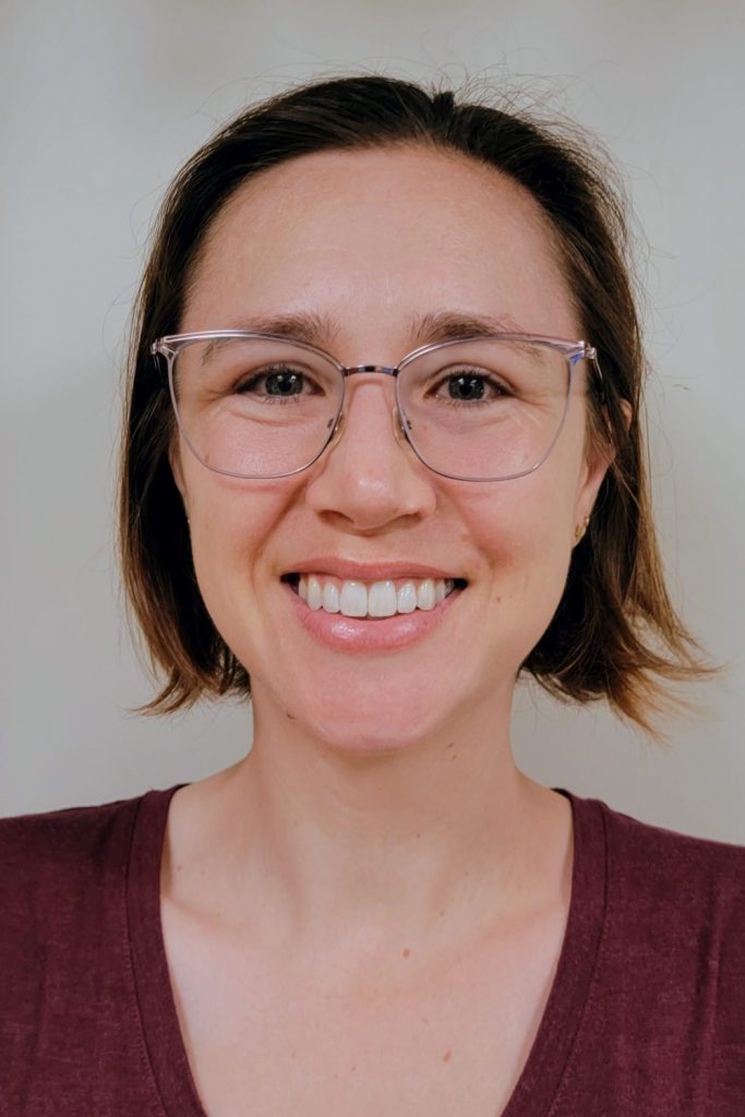 Portrait photograph of Kristen Hornung, a white woman with chin-length brown hair and glasses